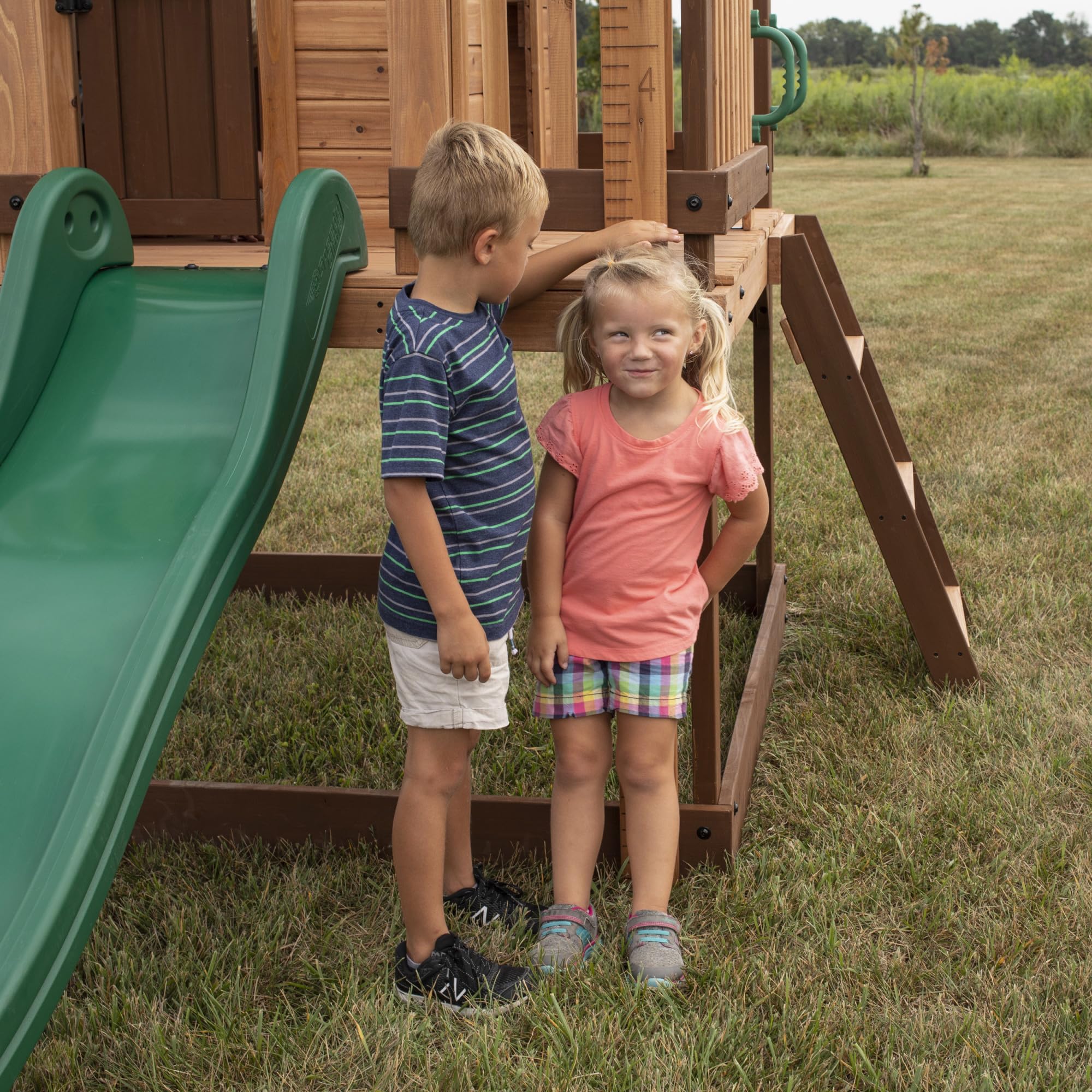 Backyard Discovery Echo Heights Elevated Cedar Wooden Kids Playhouse with Wave Slide, Play Kitchen, Wrap-Around Deck, Flat-Step Ladder, Half Door, Windows, Bell, and Growth Chart for Outdoor Play