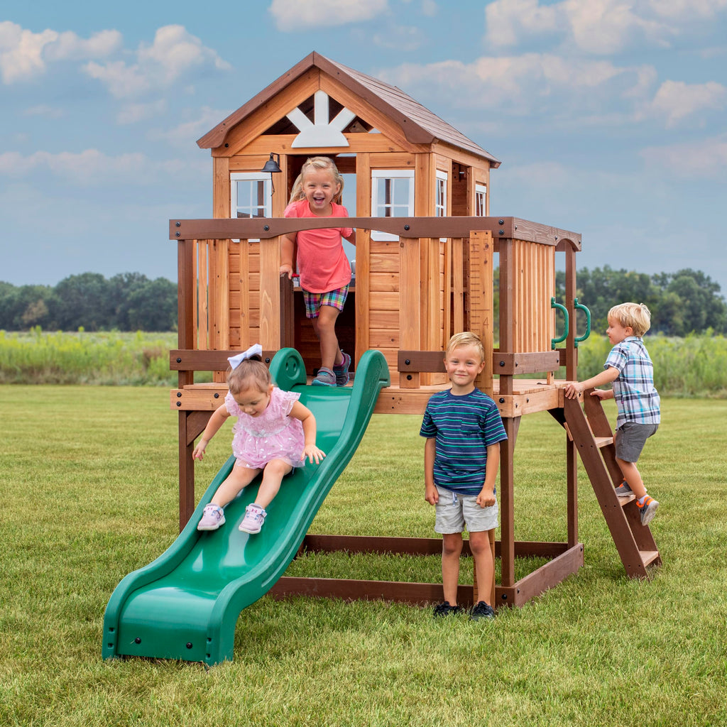 Backyard Discovery Echo Heights Elevated Cedar Wooden Kids Playhouse with Wave Slide, Play Kitchen, Wrap-Around Deck, Flat-Step Ladder, Half Door, Windows, Bell, and Growth Chart for Outdoor Play